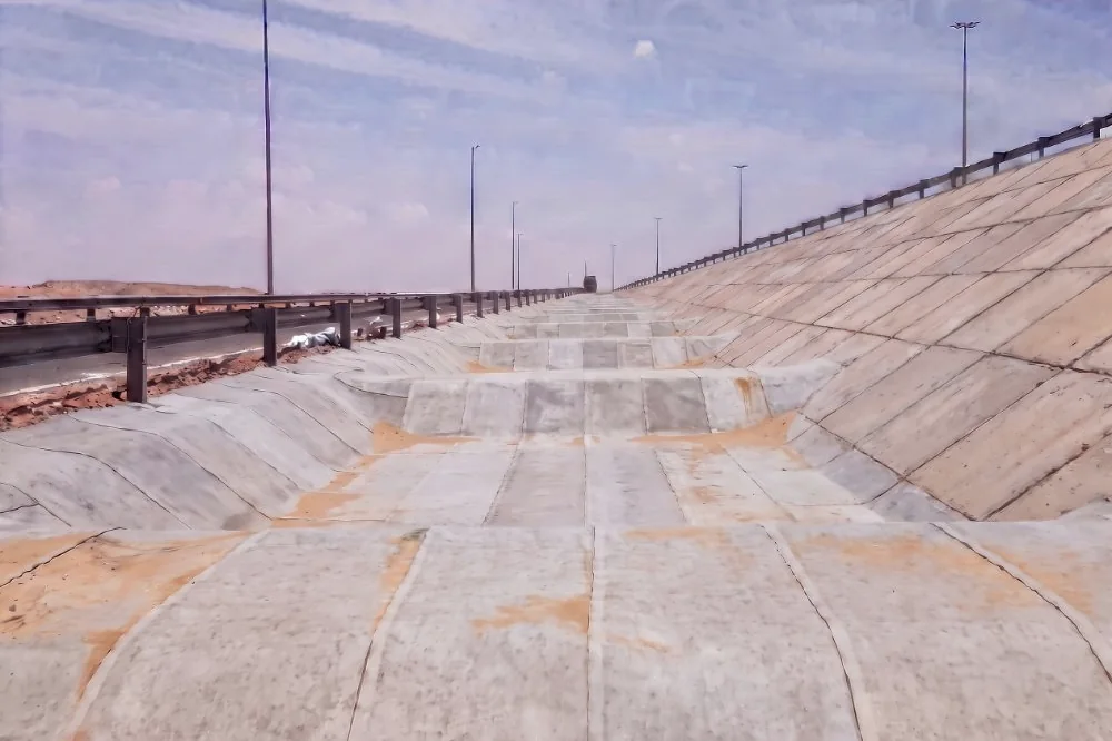 The same channel lined with pale grey cement-fabric sheeting following every terrace and slope