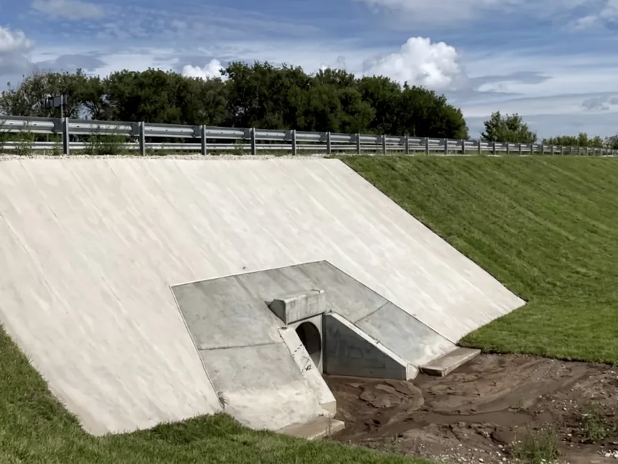 A culvert headwall and its approach slopes faced with the lining, mown grass either side