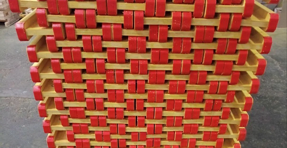 End view of stacked packs of girders, ends aligned and fitted with red end caps